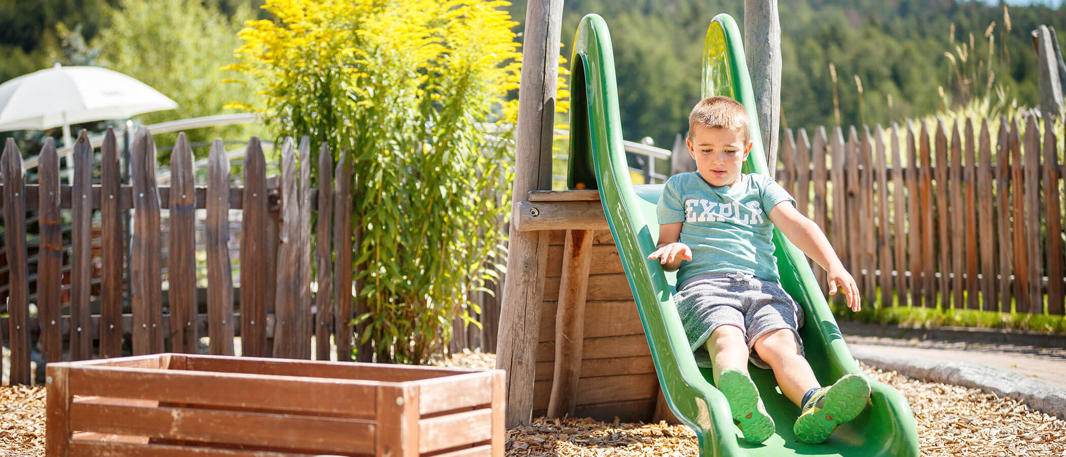 Playground - boy slides down a green slide - Hotel Amaten