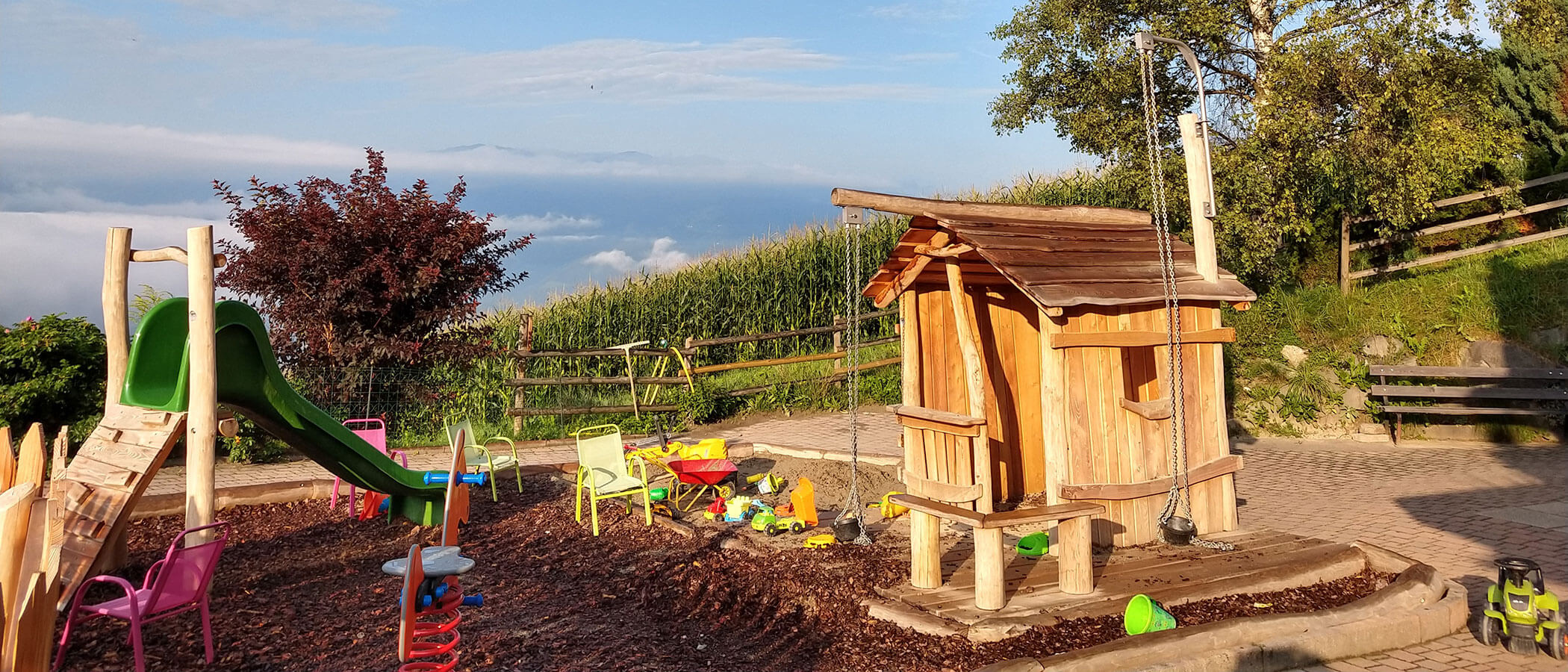 Parco giochi all'aperto con cespuglio e capanna in legno - Hotel Amaten